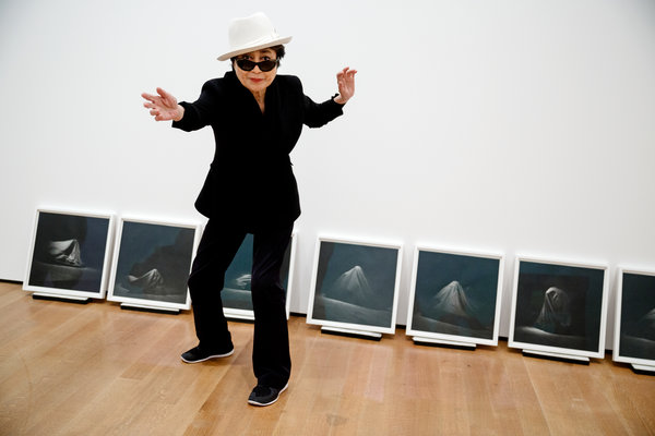 Yoko Ono at MoMA in front of photographs of a 1965 performance of Bag Piece; photo credit Richard Perry for The New York Times