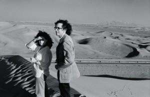 February 1979. Christo and Jeanne-Claude survey the desert from their vantage on top of a dune in the UAE desert. In the background are the Al Hajah mountains. Photo: Wolfgang Volz © 1979 Christo